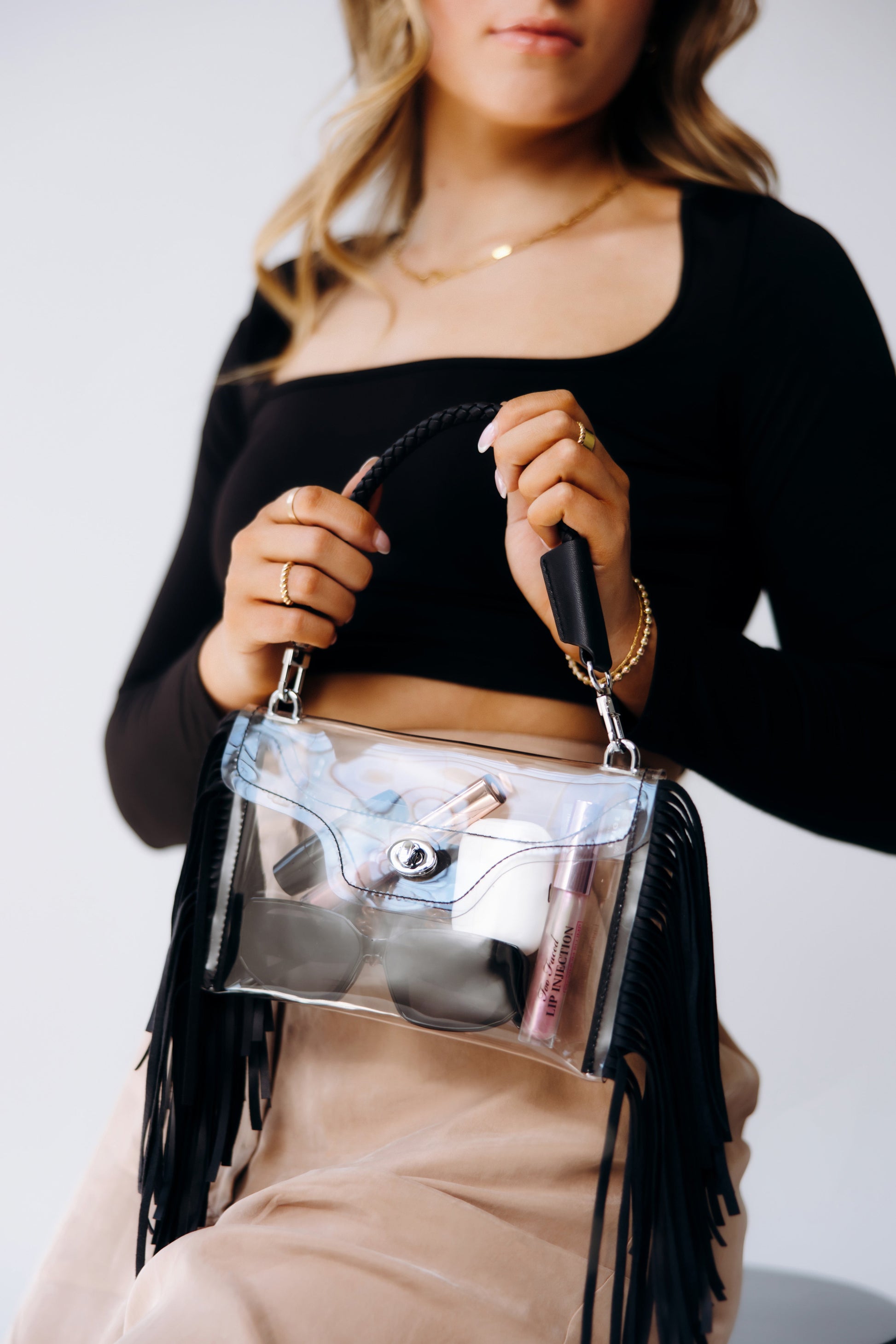 Woman sitting holding a Clear Fringe Crossbody with black detailing - Margo Paige